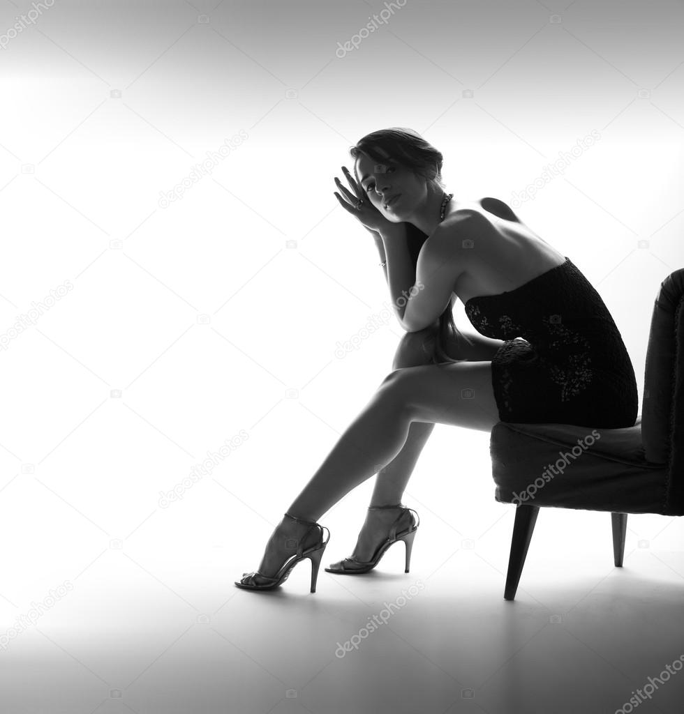 Beautiful and sexy girl sits, high heel shoes, back light