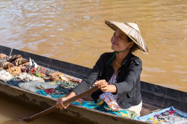 Hediyelik eşya, ıvır zıvır ve bijouterieat inle gölü, Myanmar, Burma üzerinde yüzen pazar satan küçük uzun ahşap tekne üzerinde Birmanya kadın