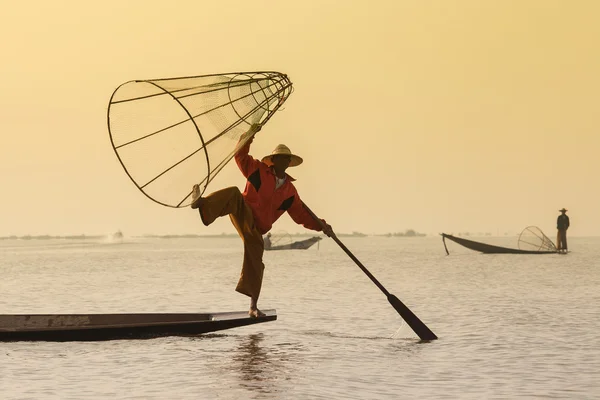 Pescador birmanês em barco de bambu captura de peixe de forma tradicional com rede artesanal. Lago Inle, Mianmar, Birmânia — Fotografia de Stock