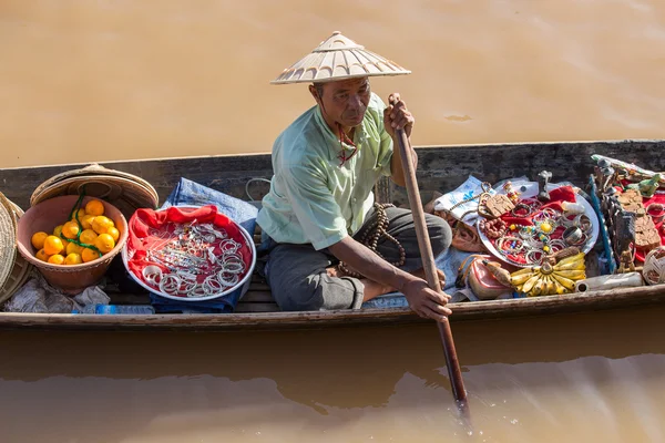 Hombre birmano en un pequeño barco largo de madera que vende recuerdos, baratijas y bijouterie en el mercado flotante en el lago Inle, Myanmar, Birmania . — Foto de Stock