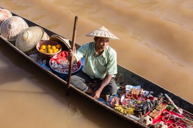 Küçük uzun ahşap teknede satış Hatıra Eşyası, ıvır zıvır ve mücevherat kayan piyasada Inle Gölü, Myanmar, Burma, Birmanya adam.