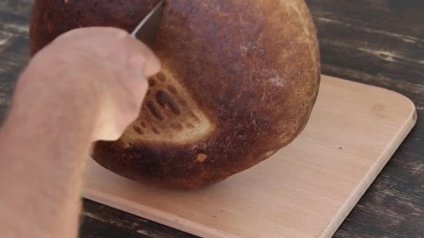 Rebanando pan de grano entero en la mesa de madera, vista superior. De cerca. — Vídeo de stock