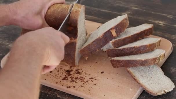 Rebanando pan integral en una mesa de madera. De cerca. — Vídeo de stock