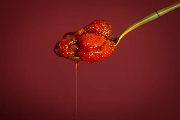 빨간색 배경에 딸기 잼 스푼 — 스톡 사진