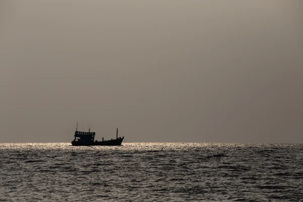 Barco silhueta e pôr do sol sobre a água do mar — Fotografia de Stock