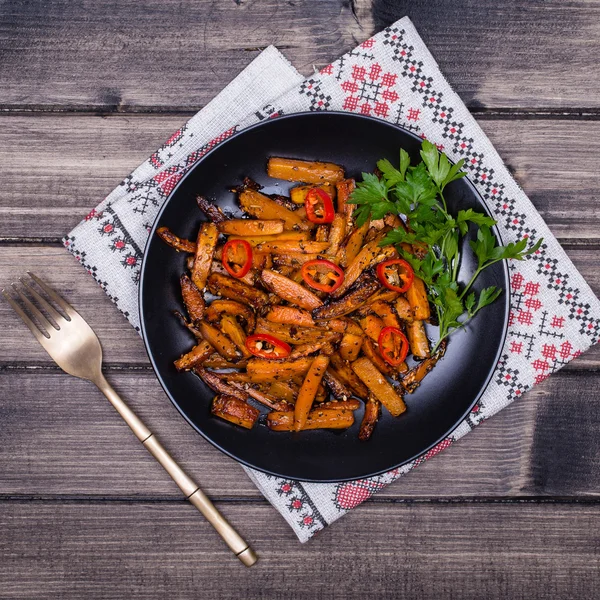 Roasted carrots in black plate, close up — Stock Photo, Image