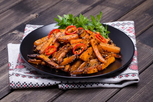 Roasted carrots in black plate, close up — Stock Photo, Image