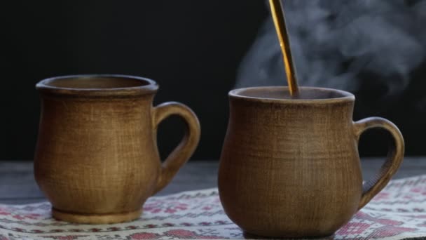 Dva hliněné pohárek s černým čajem. Káva nebo čaj. Pár hnědých šálků horkého nápoje v černém pozadí 