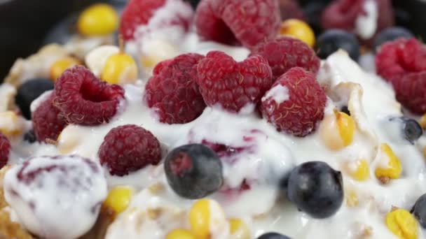 Cereal flakes with blueberries, raspberries and sea buckthorn rotating . Crunchy tasty muesli food background close up — Stock Video