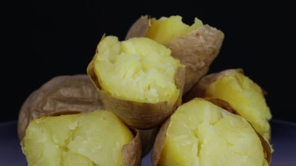 Ukrainisches Nationalgericht sind Ofenkartoffeln. Kartoffel auf schwarzem Hintergrund dreht sich, Nahaufnahme — Stockvideo