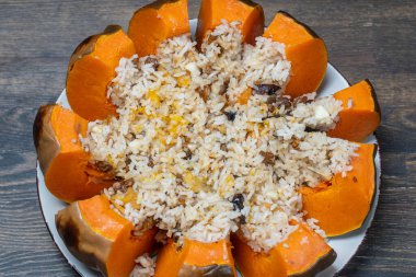 Harika bir balkabağı, tabakta yakın plan dolgu malzemesi, üst manzara. Doldurulmuş portakal kabağı, tam pişmiş pirinç, kuru üzüm ve baharat karışımı.