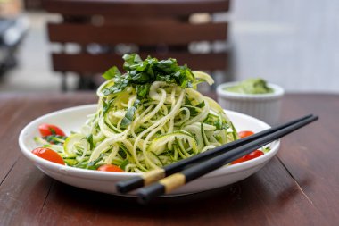Erişte sarmısaklı kabak, salatalık, vişneli domates, avokado soslu sarımsak. Vietnam, vejetaryen için çiğ yemek. Kapat.