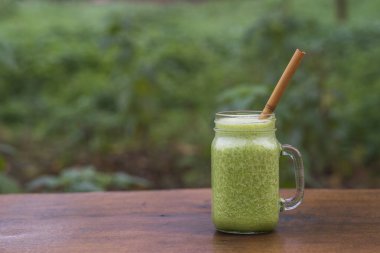 Yeşil maydanoz, avokado, bal ve muz. Bir bahçe kafesinde, ahşap bir masada, cam bardakta. Yakın plan. Sağlıklı gıda konsepti