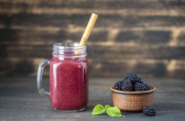 Ahşap arka plandaki cam kavanozda taze böğürtlen smoothie, yakın çekim. Sağlıklı gıda konsepti