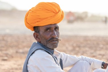 PUSHKAR, INDIA - 12 Kasım 2018: Hindistan 'ın kutsal şehri Pushkar, Rajasthan yakınlarındaki Pushkar Camel Mela sırasında çöldeki Hintli adam. Bu fuar dünyanın en büyük deve ticaret fuarı..