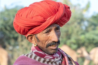 PUSHKAR, INDIA - 14 Kasım 2018: Hindistan 'ın kutsal şehri Pushkar, Rajasthan yakınlarındaki Pushkar Camel Mela sırasında çöldeki Hintli adam. Bu fuar dünyanın en büyük deve ticaret fuarı..