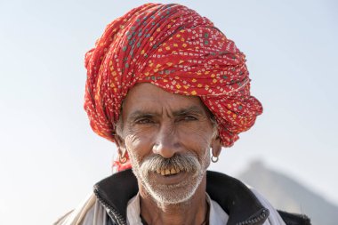 PUSHKAR, INDIA - 13 Kasım 2018: Hindistan 'ın kutsal şehri Pushkar, Rajasthan yakınlarındaki Pushkar Camel Mela sırasında çöldeki Hintli adam. Bu fuar dünyanın en büyük deve ticaret fuarı..