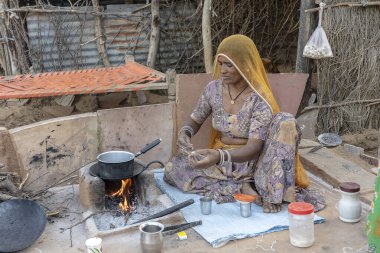 PUSHKAR, INDIA - 13 Kasım 2018: Hindistan 'da çölün yakınındaki Thar, Rajasthan' da ailesi için çay yapan Hintli kadın
