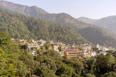 RISHIKESH, INDIA - NOVEMBER 05, 2018: Rishikesh, Hindistan 'da Ganga nehri yakınlarındaki bir yamaçtaki güzel evler