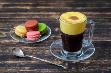 Çiğ yumurta sarısı ve yoğunlaştırılmış sütten yapılmış geleneksel Vietnam yumurtası kahvesi, yakın çekim. Ahşap masa arkasında yumurta kahvesi.
