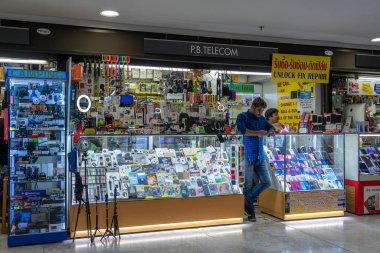BANGKOK, THAILAND - 23 Mayıs 2019: Bangkok, Tayland 'da bir elektronik ve cep telefonu mağazasında çalışan adam. Genç satıcı danışmanı tezgahın arkasında duruyor.