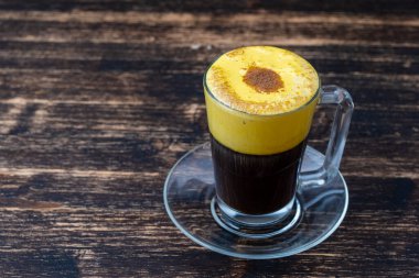 Çiğ yumurta sarısı ve yoğunlaştırılmış sütten yapılmış geleneksel Vietnam yumurtası kahvesi, yakın çekim. Ahşap masa arkasında yumurta kahvesi.