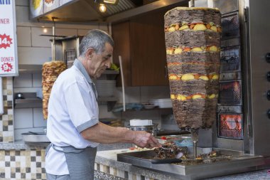 Bodrum, Türkiye - Eylül 09, 2019: Türk şef, Türkiye 'nin eski Bodrum kentindeki bir caddedeki bir kebap dükkanında döner kebapçı et dilimledi