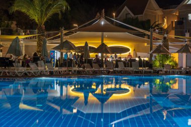 Didim, Türkiye - Eylül 02, 2019: Aydınlatılmış yüzme havuzu gece plajdaki turistik otelin yanında. Didim, Hindi. Tatil ve seyahat kavramı