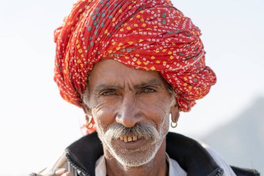 PUSHKAR, INDIA - 13 Kasım 2018: Hindistan 'ın kutsal şehri Pushkar, Rajasthan yakınlarındaki Pushkar Camel Mela sırasında çöldeki Hintli adam. Bu fuar dünyanın en büyük deve ticaret fuarı..