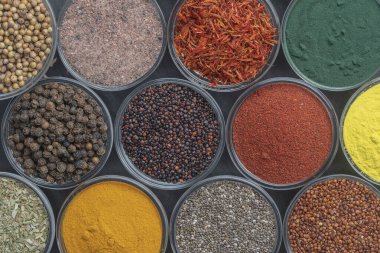 Arka planda farklı baharatlar ve otlar, yakın plan, üst manzara. Renkli baharatlar, tohumlar ve yemek pişirmek için bitkiler.