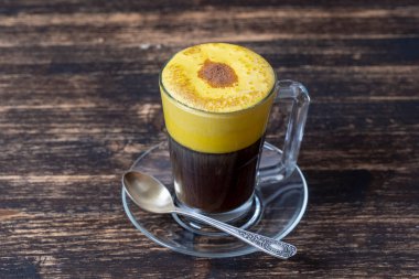 Çiğ yumurta sarısı ve yoğunlaştırılmış sütten yapılmış geleneksel Vietnam yumurtası kahvesi, yakın çekim. Ahşap masa arkasında yumurta kahvesi.