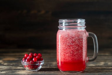 Duvarcı kavanozunda kızılcık ve inek üzümü suyu. Masadaki cam bardakta taze organik kırmızı smoothie, yakın çekim. Yaz meyvelerini tazeliyorum. Sağlıklı beslenme kavramı. Boşluğu kopyala