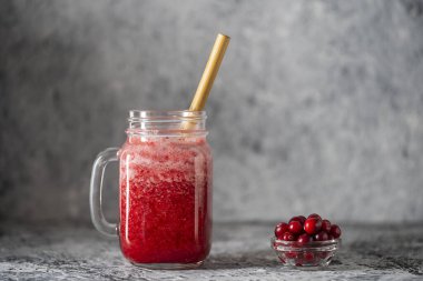 Bambu pipetli kızılcık ve inek meyveli buzlu içecek. Masadaki cam bardakta taze organik kırmızı smoothie, yakın çekim. Yaz meyvelerini tazeliyorum. Sağlıklı beslenme kavramı. Boşluğu kopyala