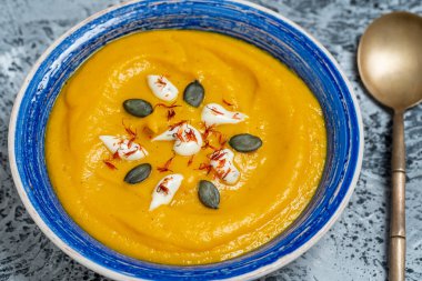 Kavrulmuş balkabağı ve kremalı havuç çorbası ve kabak çekirdeği. Kapat.