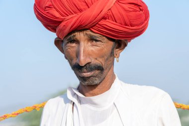 PUSHKAR, INDIA - 14 Kasım 2018: Hindistan 'ın kutsal şehri Pushkar, Rajasthan yakınlarındaki Pushkar Camel Mela sırasında çöldeki Hintli adam. Bu fuar dünyanın en büyük deve ticaret fuarı..