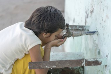RISHIKESH, INDIA - 06, 2018: Hintli susamış bir kızın portresi Rishikesh, Hindistan 'da sokak musluğundan su içiyor