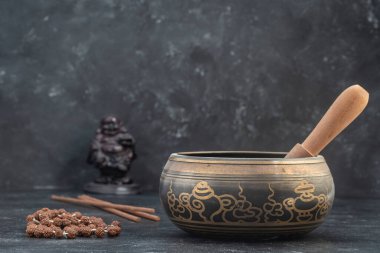 Gri arka planda tahta sopa ve tibet boncuklu tespih kasesi. Meditasyon, yoga, kendini geliştirme ve ses terapisi konsepti. Kapat, boşluğu kopyala