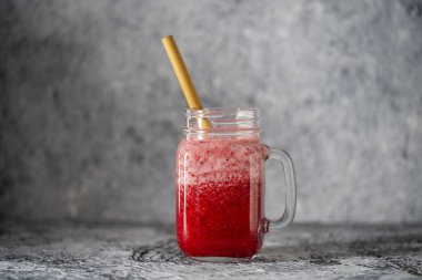 Bambu pipetli kızılcık ve inek meyveli buzlu içecek. Masadaki cam bardakta taze organik kırmızı smoothie, yakın çekim. Yaz meyvelerini tazeliyorum. Sağlıklı beslenme kavramı. Boşluğu kopyala