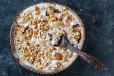 Yulaf ezmeli granola, kurutulmuş meyve, bal, kuru üzüm, kızılcık, hindistan cevizi kabında yoğurt ve kaju fıstığı, yakın plan, üst manzara. Sağlıklı kahvaltı kavramı
