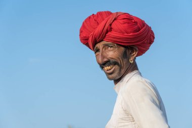 PUSHKAR, INDIA - 14 Kasım 2018: Hindistan 'ın kutsal şehri Pushkar, Rajasthan yakınlarındaki Pushkar Camel Mela sırasında çöldeki Hintli adam. Bu fuar dünyanın en büyük deve ticaret fuarı..