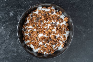 Yulaf ezmeli granola, kurutulmuş meyve, bal, kuru üzüm, çikolata cipsi, badem ve yoğurtlu fındık, yakın çekim, üst manzara. Sağlıklı kahvaltı kavramı