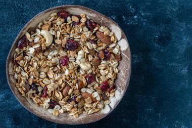 Yulaf ezmeli granola, kurutulmuş meyve, bal, kuru üzüm, kızılcık, hindistan cevizi kabında badem ve fındık, yakın çekim, üst manzara. Sağlıklı kahvaltı kavramı