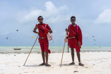 Zanzibar, Tanzanya - 15 Ocak 2020: Geleneksel kıyafetler giymiş iki Afrikalı adam okyanus kenarında, Tanzanya, Doğu Afrika 'daki Zanzibar adasının kumsalında duruyor.