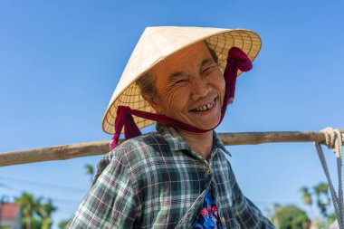 Hoi An, Vietnam - 7 Temmuz 2020: Hoi An şehri yakınlarındaki bir vejetaryen köyünde saman şapkalı yaşlı kadın