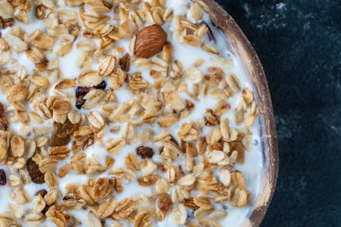 Yulaf ezmeli granola, kurutulmuş meyve, bal, kuru üzüm, kızılcık, hindistan cevizi kabında yoğurt ve kaju fıstığı, yakın plan, üst manzara. Sağlıklı kahvaltı kavramı