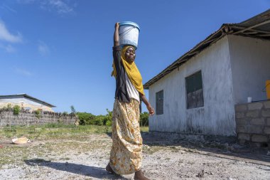 Zanzibar, Tanzanya - 14 Ocak 2020: Tanzanya, Doğu Afrika 'daki Zanzibar Adası' nda bir sokakta tanımlanamayan Afrikalı kız ve kova
