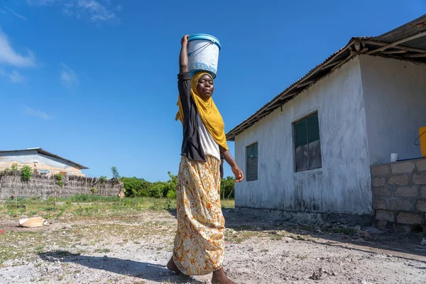 坦桑尼亚桑给巴尔 2020年1月14日 在坦桑尼亚桑给巴尔岛的一条街上 一名身份不明的非洲女孩和一个装有水的桶 — 图库照片