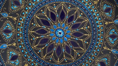 Dekoratif seramik tabak, siyah, mavi ve altın renkli, arka planda boyalı, yakın plan, üst manzara, döndürme. Akrilik boyalarla boyanmış dekoratif porselen tabaka, el işi, nokta boyası.