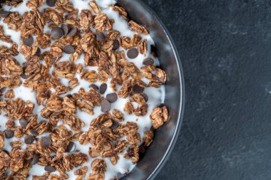 Yulaf ezmeli granola, kurutulmuş meyve, bal, kuru üzüm, çikolata cipsi, badem ve yoğurtlu fındık, yakın çekim, üst manzara. Sağlıklı kahvaltı kavramı