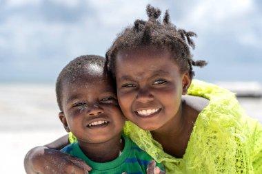 Zanzibar, Tanzanya - 12 Aralık 2019: Genç mutlu Afrikalı kız ve oğlan Doğu Afrika 'daki Tanzanya' nın Zanzibar adasındaki tropik plajda deniz suyu yakınında.
